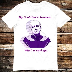 以下が含まれることがあります： 白地に紫と白の男性のイラストが描かれたTシャツで、"By Grabthar's hammer... What a savings."というテキストが書かれています