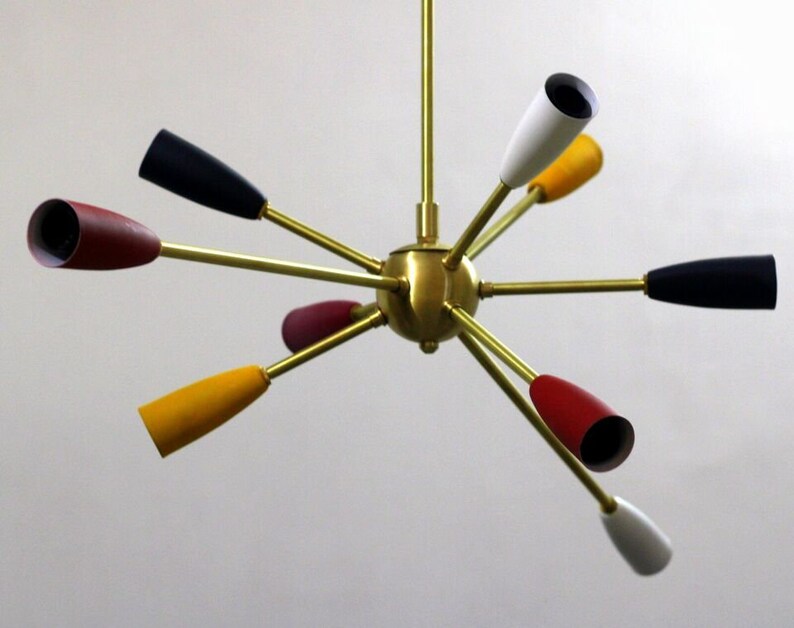 May include: A brass ceiling light fixture with eight arms, each with a different coloured cone-shaped shade. The shades are red, yellow, white, and black.