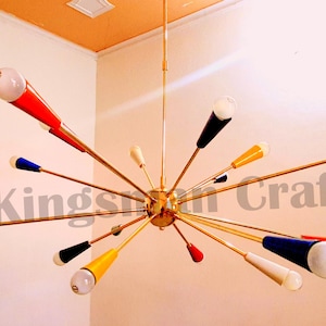 Peut inclure: Un lustre moderne du milieu du siècle, de couleur or, avec de multiples bras s'étendant vers l'extérieur. Chaque bras est doté d'un abat-jour en verre coloré, rouge, bleu, jaune et blanc.