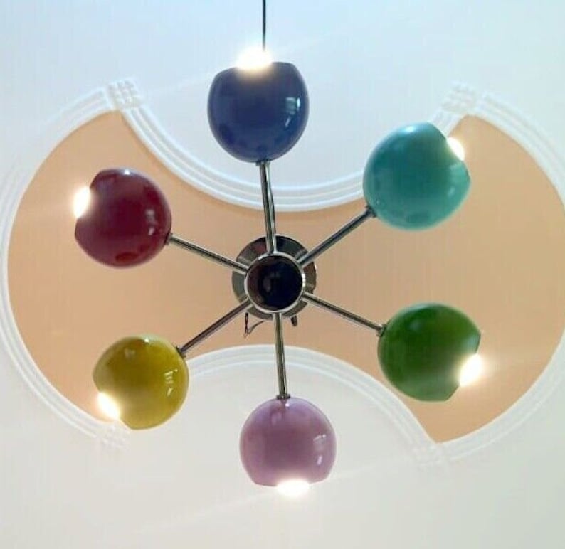 May include: A six-light chandelier with colorful glass shades. The shades are red, yellow, green, blue, and purple. The chandelier has a chrome finish.