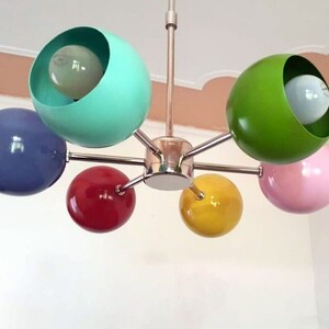 May include: A six-light chandelier with colorful globe-shaped shades. The shades are blue, green, yellow, pink, and red.