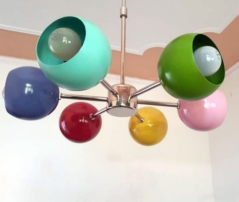 May include: A six-light chandelier with colorful globe-shaped shades. The shades are blue, green, yellow, pink, and red.
