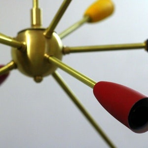 May include: A brass ceiling light fixture with six arms. Each arm has a coloured glass shade. The shades are red, yellow, and blue.