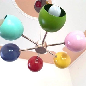 May include: A six-light chandelier with colorful round shades. The shades are green, pink, blue, yellow, red, and turquoise.