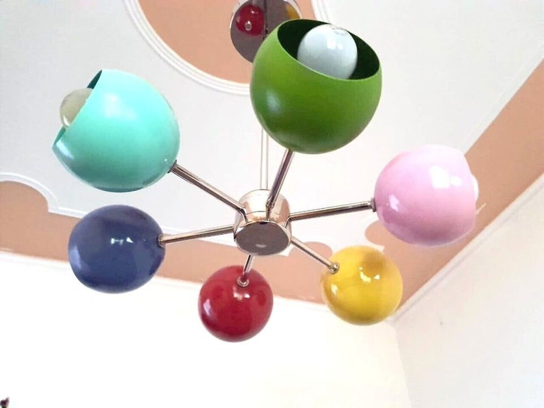 May include: A six-light chandelier with colorful round shades. The shades are green, pink, blue, yellow, red, and turquoise.