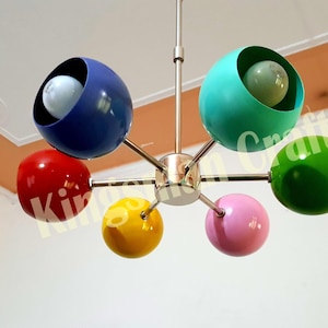May include: A six-light ceiling fixture with colorful glass shades. The shades are red, yellow, green, blue, pink, and turquoise. The fixture is made of metal and has a chrome finish.