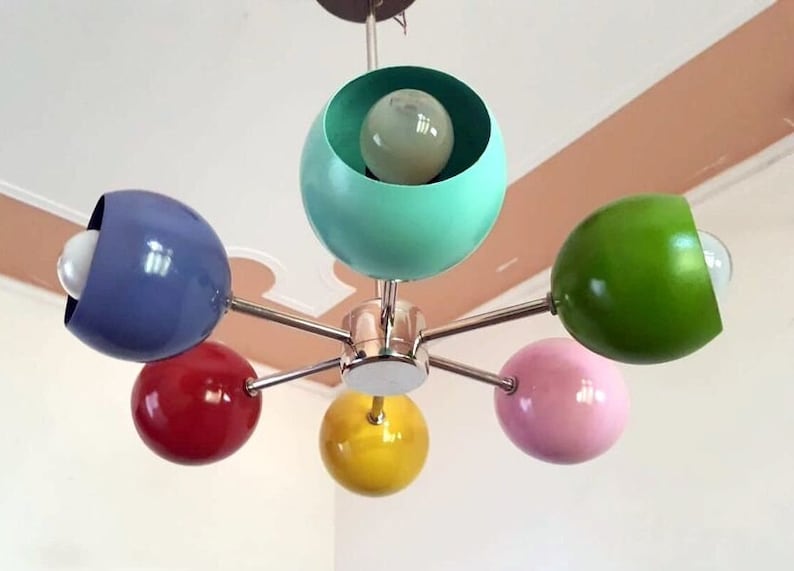 May include: A six-light chandelier with colorful spherical shades. The shades are blue, green, red, yellow, and pink. The chandelier has a chrome finish.