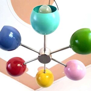 May include: A six-light chrome chandelier with colorful globe-shaped shades. The shades are blue, green, yellow, pink, red, and turquoise.