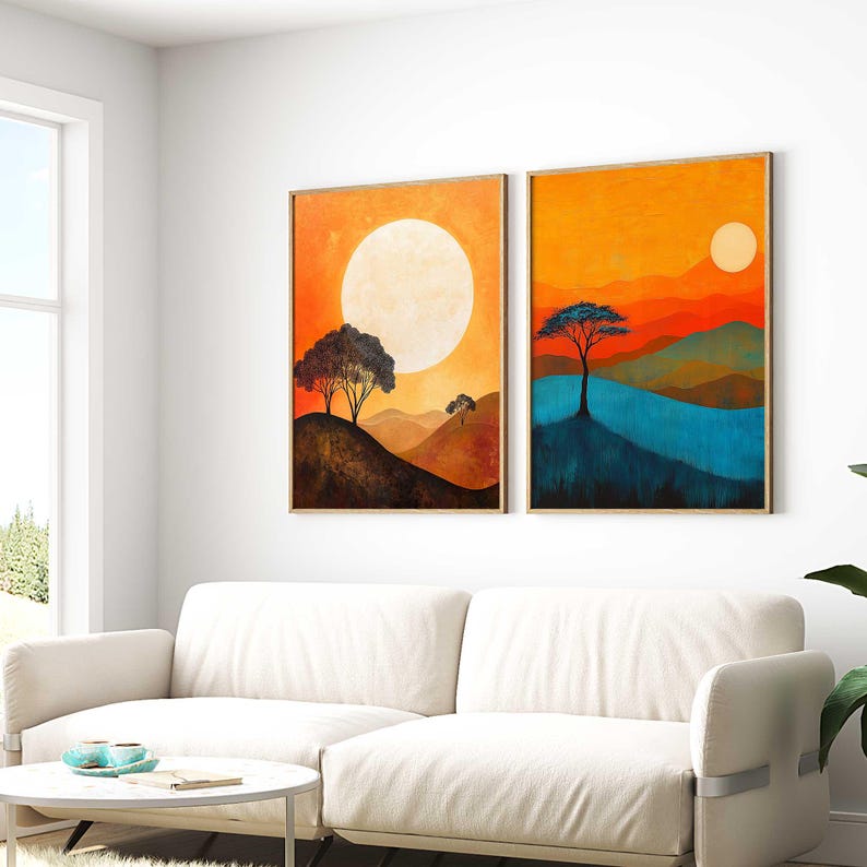 May include: Two framed abstract landscape paintings with a sunset theme. The paintings feature a large orange sun, a blue lake, and silhouetted trees against a backdrop of orange, red, and green hills.