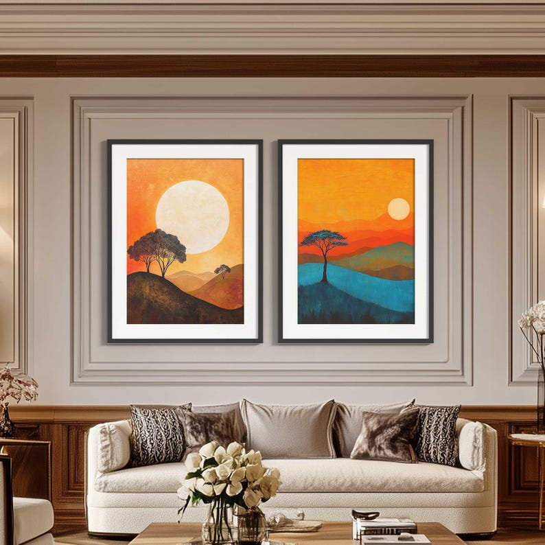 May include: Two framed landscape paintings with a sunset theme. The paintings feature a silhouette of trees and hills with a large sun in the sky. One painting has a blue and green color scheme, while the other has a brown and orange color scheme.