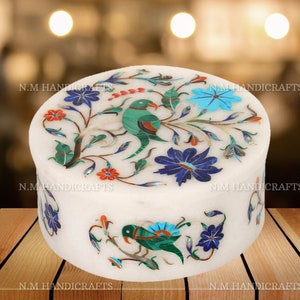 May include: A white marble trinket box with a floral design inlaid with colorful gemstones. The design features two birds and flowers in shades of blue, green, red, and orange.