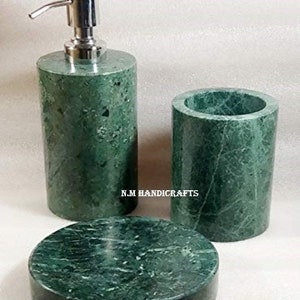 Op de afbeelding: Groene marmeren badkamerset met een zeepdispenser, een beker en een zeepbakje. De set is gemaakt van groen marmer met witte aderen.