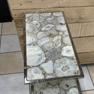 May include: A two-tiered side table with a silver metal frame and agate stone tops. The agate stone is white with gray and brown veins.