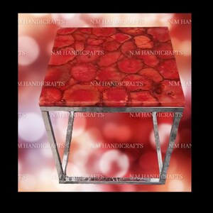 May include: A square end table with a red agate top and a silver metal frame. The agate top has a unique pattern of red and orange swirls.