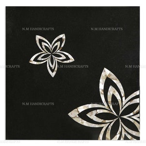 Könnte beinhalten: Schwarze quadratische Fliese mit zwei weißen Perlmutt-Blumenmustern. Die Fliese ist mit komplizierten Blumenmustern verziert und hat eine polierte Oberfläche.