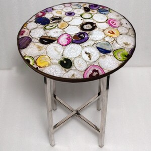 May include: A round side table with a mosaic top made of colorful agate slices. The table has a dark brown rim and a silver metal base. The agate slices are white, pink, purple, green, and blue. The table is approximately 20 inches in diameter.