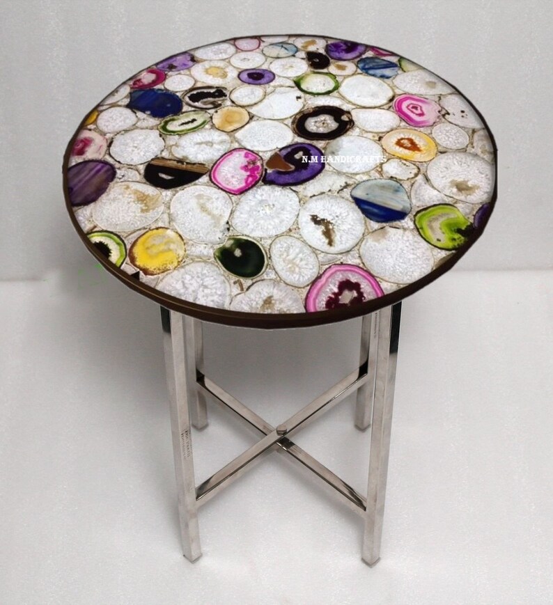 May include: A round side table with a mosaic top made of colorful agate slices. The table has a dark brown rim and a silver metal base. The agate slices are white, pink, purple, green, and blue. The table is approximately 20 inches in diameter.