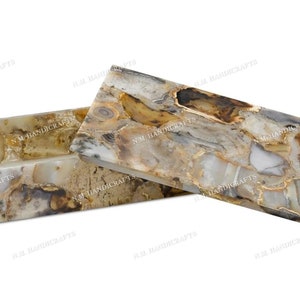 May include: A rectangular agate stone box with a lid. The box and lid are both made of agate stone with a natural pattern of brown, white, and gray. The box is open and the lid is sitting next to it.