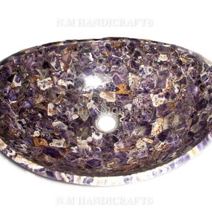 Op de afbeelding: Een ovale wastafel gemaakt van een mozaïek van paarse amethist. De wastafel heeft een klein afvoergat in het midden.