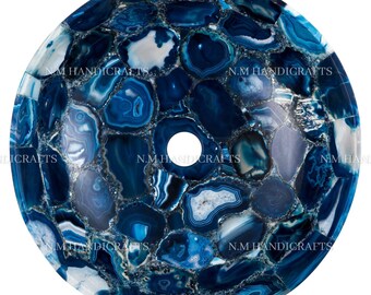 Könnte beinhalten: Ein rundes blaues Achat-Waschbecken mit einem Loch in der Mitte. Das Waschbecken besteht aus vielen kleinen Achatstücken, die miteinander verklebt wurden. Das Waschbecken ist ein wunderschönes und einzigartiges Kunstwerk.