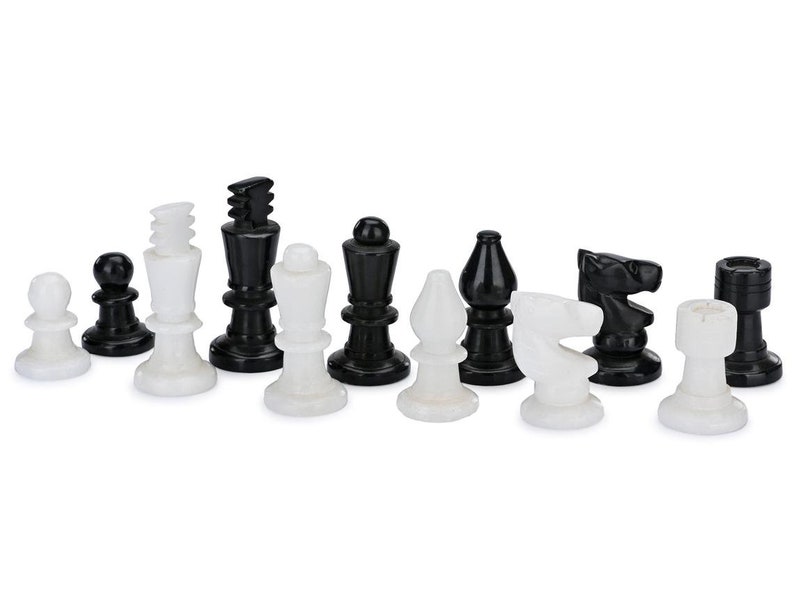 May include: A set of black and white chess pieces made of marble. The pieces are arranged in a row on a white background.