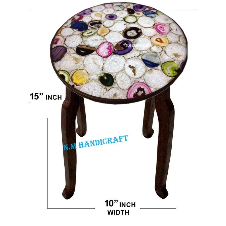 May include: A round decorative stool with a top made of colorful agate slices. The stool has dark brown curved legs and measures 15 inches in diameter and 10 inches wide.