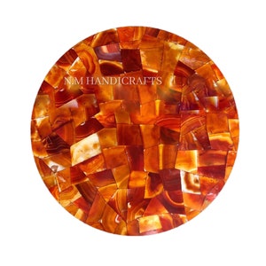May include: Round, orange agate table top made of many small pieces of agate. The table top is approximately 12 inches in diameter. The agate is a natural stone with a variety of colors and patterns. The table top is perfect for a small table or as a decorative piece.