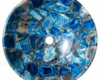 May include: A round blue agate stone sink with a drain hole in the center. The sink is made of many small pieces of agate that have been glued together to create a mosaic pattern.