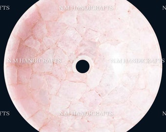 May include: A round pink quartz sink with a drain hole in the center. The sink is made of many small pieces of quartz that have been pieced together. The sink is surrounded by a black background. The text "N.M HANDICRAFTS" is visible on the sink.