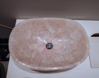 May include: A pink oval-shaped sink made of mosaic tiles. The sink has a drain in the center.