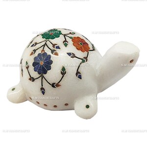 Può includere: Figurina di tartaruga in marmo bianco con intricati disegni floreali intarsiati con pietre colorate. La tartaruga ha un guscio dettagliato con fiori e viti in tonalità di blu, verde, arancio e rosso.