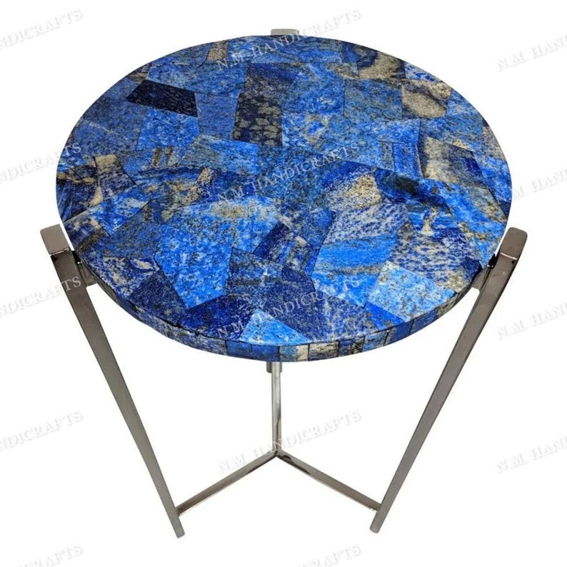 May include: A round side table with a lapis lazuli mosaic top and a silver metal base. The table has a modern design and is perfect for a living room or bedroom.