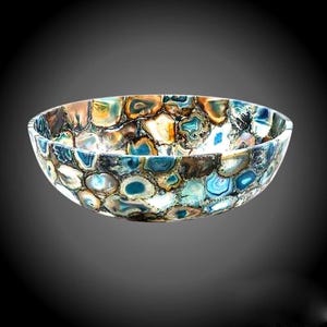 Puede incluir: Un tazón grande y redondo hecho de piedra de ágata. El tazón tiene un esquema de color azul, verde y marrón con un patrón de remolino.