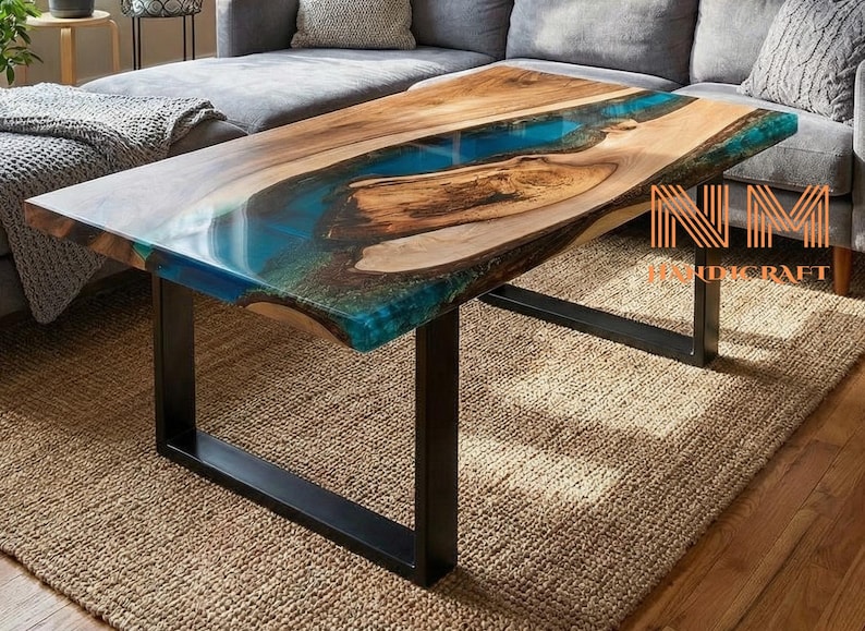 May include: A rectangular coffee table featuring a natural live-edge wood slab with a central translucent blue resin river inlay. The table is supported by a black metal frame and includes the text NM HANDICRAFT in orange.