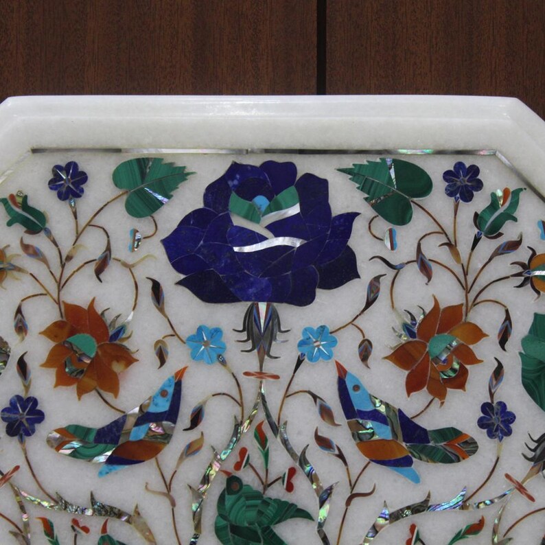 May include: White marble tray with intricate floral designs inlaid with colourful gemstones, including blue, green, red, and gold. The tray features a central rose with a blue centre and green leaves.
