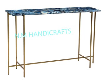 May include: A blue agate console table with a gold metal frame. The table has a rectangular top and a simple, modern design. N.M HANDICRAFTS is printed on the table.