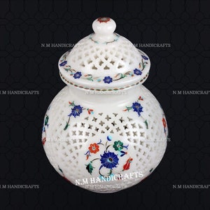 May include: White marble jar with a lid, featuring intricate floral designs and a cut-out pattern. The jar is decorated with colorful inlaid stones.