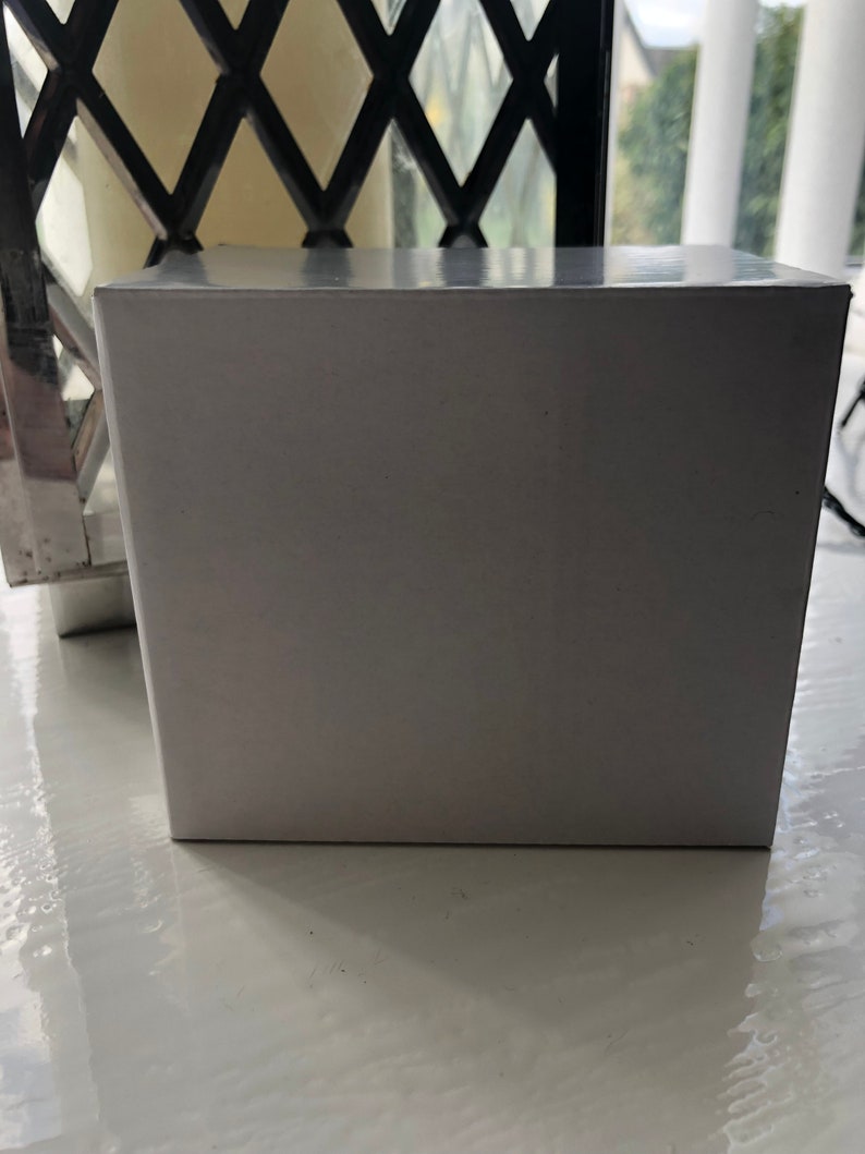 May include: A white rectangular box with a smooth, glossy surface. The box is sitting on a white surface.