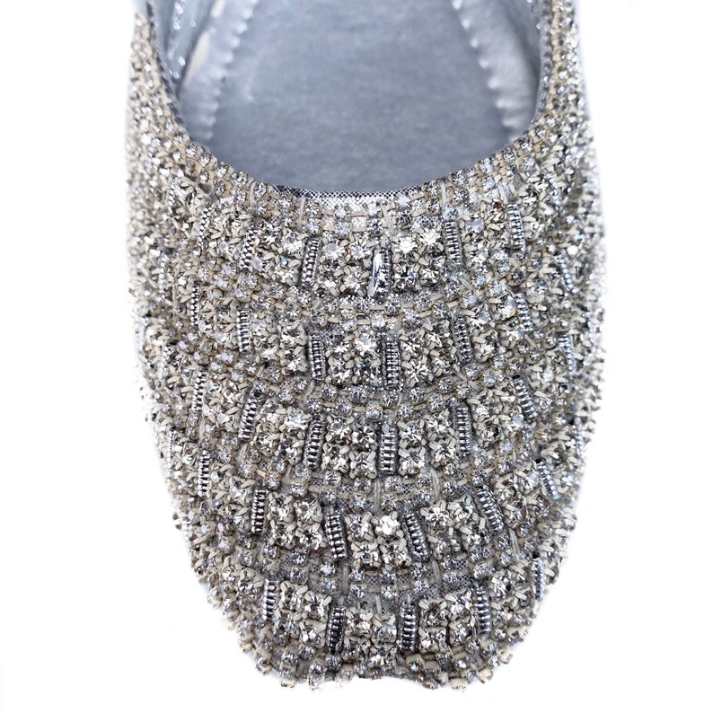 Puede incluir: Un zapato plano plateado con un dise&ntilde;o brillante de tipo cristal que cubre toda la parte superior del zapato.