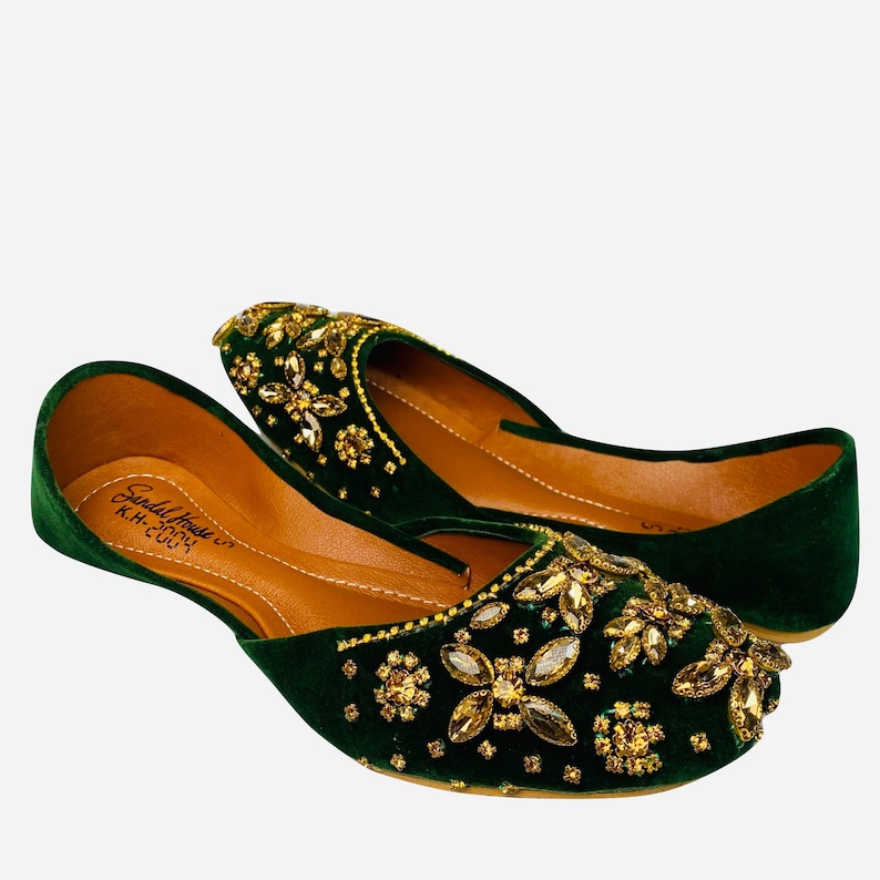 May include: A pair of green velvet shoes with gold embroidery and embellishments. The shoes have a pointed toe and a low heel. The brand name "Sandal House" is visible on the insole.