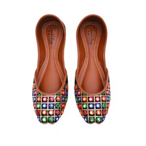 May include: A pair of black velvet flats with colorful embroidered mirror work. The shoes have a brown leather insole and the text "Sandal House, K.H - 2319" is printed on the insole.