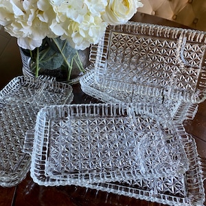May include: A set of four clear glass serving trays with a diamond pattern. The trays are stacked on top of each other.