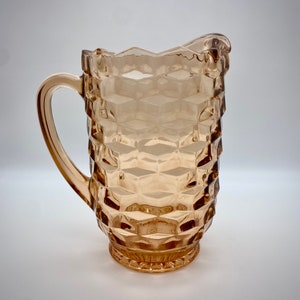 May include: A clear amber glass pitcher with a textured diamond pattern. The pitcher has a wide mouth and a handle.