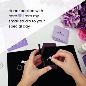 Behind-the-scenes look of hands carefully preparing an Areshna engagement ring inside a luxury purple box, showcasing small-studio craftsmanship, jewelry care guide, premium packaging, and floral details for a high-end unboxing experience.