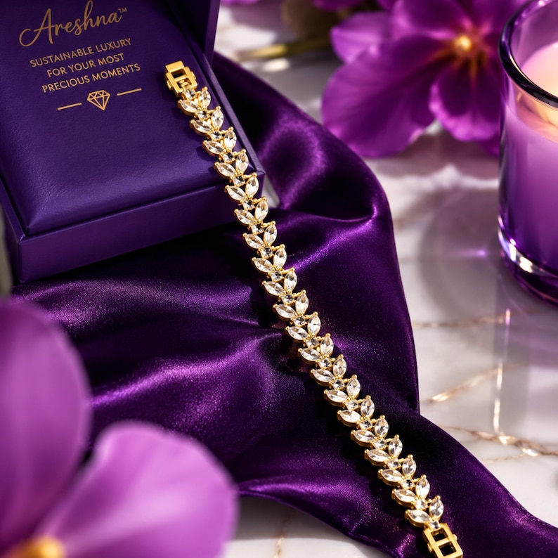 Areshna™ The Aurora 18K gold-plated crystal tennis bracelet crafted with Swarovski elements and Diamonash™ lab-created diamond simulants, showcased next to the brand's signature royal purple presentation box.