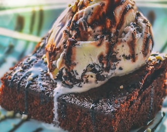 Puede incluir: Un brownie de chocolate cubierto con una bola de helado de vainilla rociado con salsa de chocolate.