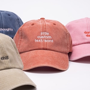 Vintage style cap with custom text embroidered on the front of it. Caps are orange, pink, khaki and denim colours.