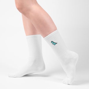 Female model wearing white cotton ribbed socks with little dinosaur embroidered on each side