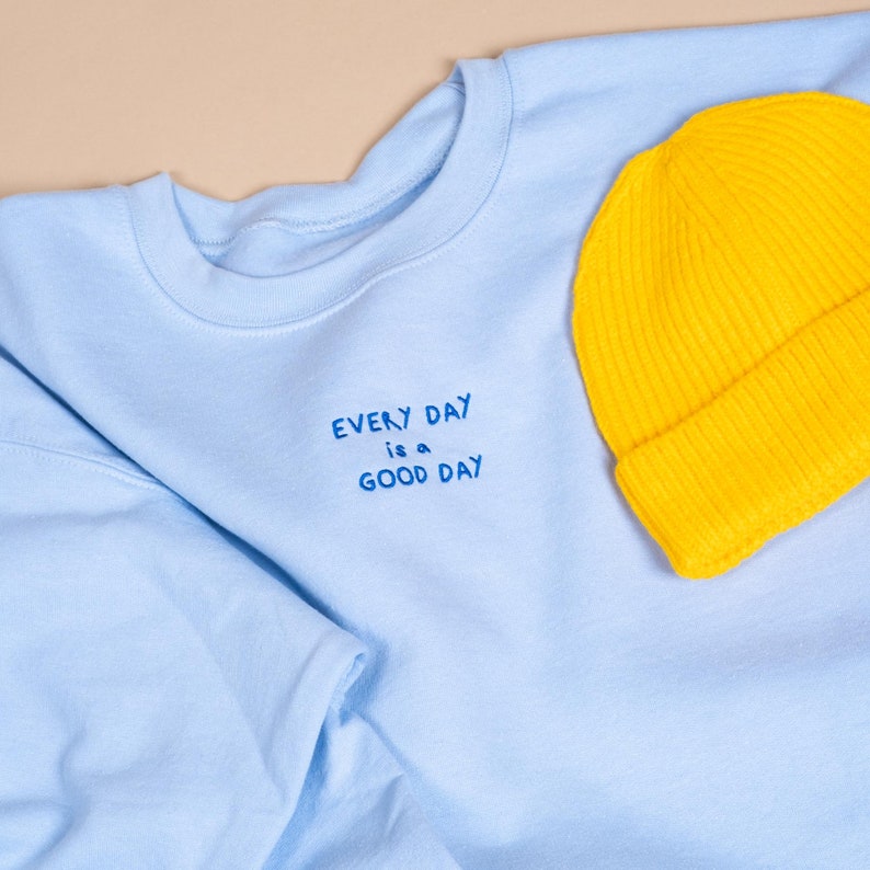 Vibrant and bright sweatshirt in blue and beanie on yellow flat layed