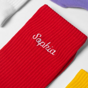 Flat lay and close up of vibrant red socks with handwritten name embroidered on them